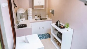 Eine kleine Küchenzeile mit Kaffeemaschine, Spüle und kleinem Kühlschrank.