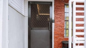 Eine geschlossene Tür mit einem Metallgitterfenster, einer Ziegelwand und einem weißen Tor.