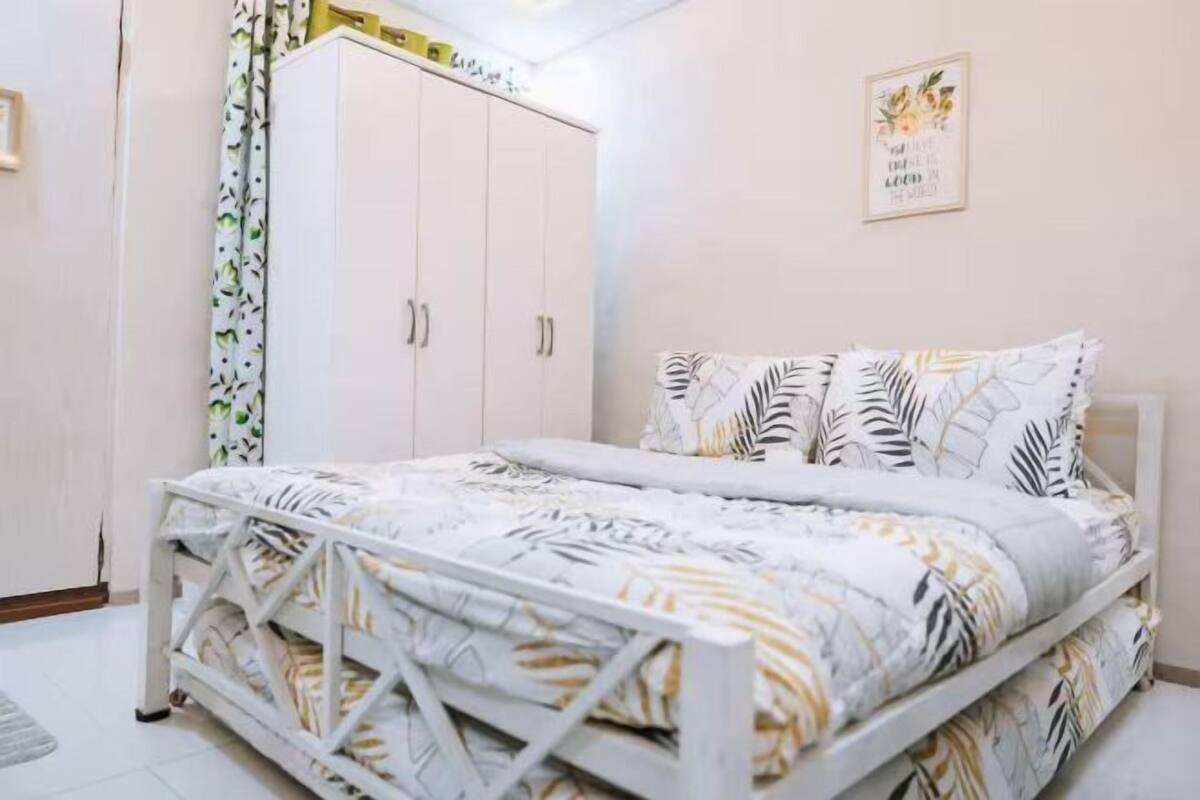 Ein Schlafzimmer mit einem Bett, einem Kleiderschrank und einer Wand mit einem gerahmten Zitat.