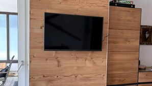 Habitació moderna amb un televisor penjat de fusta, una porta corredissa i un armari de fusta.