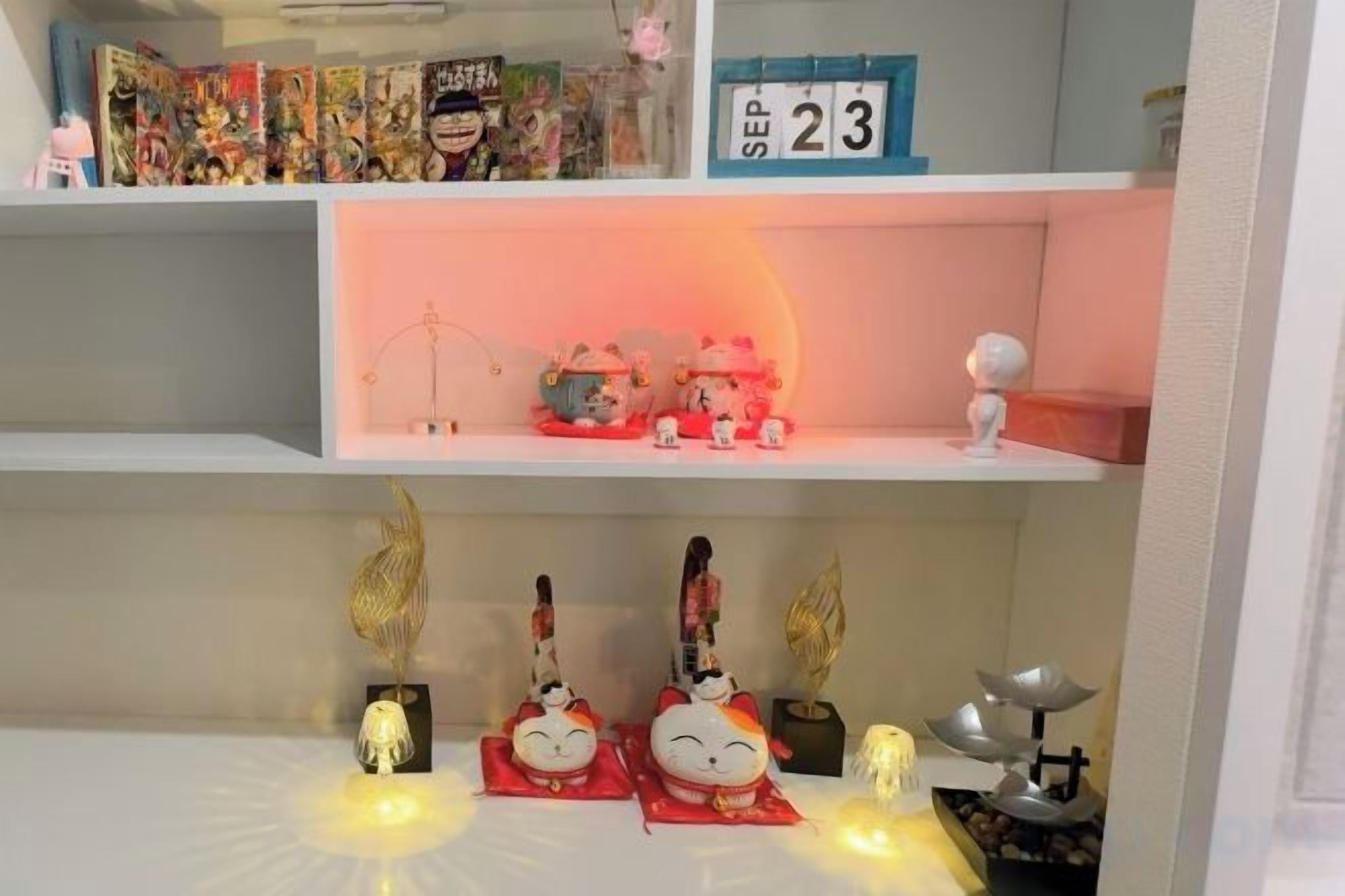 A shelf with various items including a calendar marked 'SEP 23', a small decorative item, and a shelf with figurines and a lamp.
