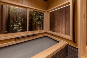 A wooden spa room with a large window, a wooden bench, and a tiled floor. - Kyoran Seigatei (Kyoto)