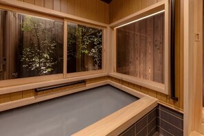 Una habitación de madera con suelo de tatami, ventanas amplias y una puerta corredera.