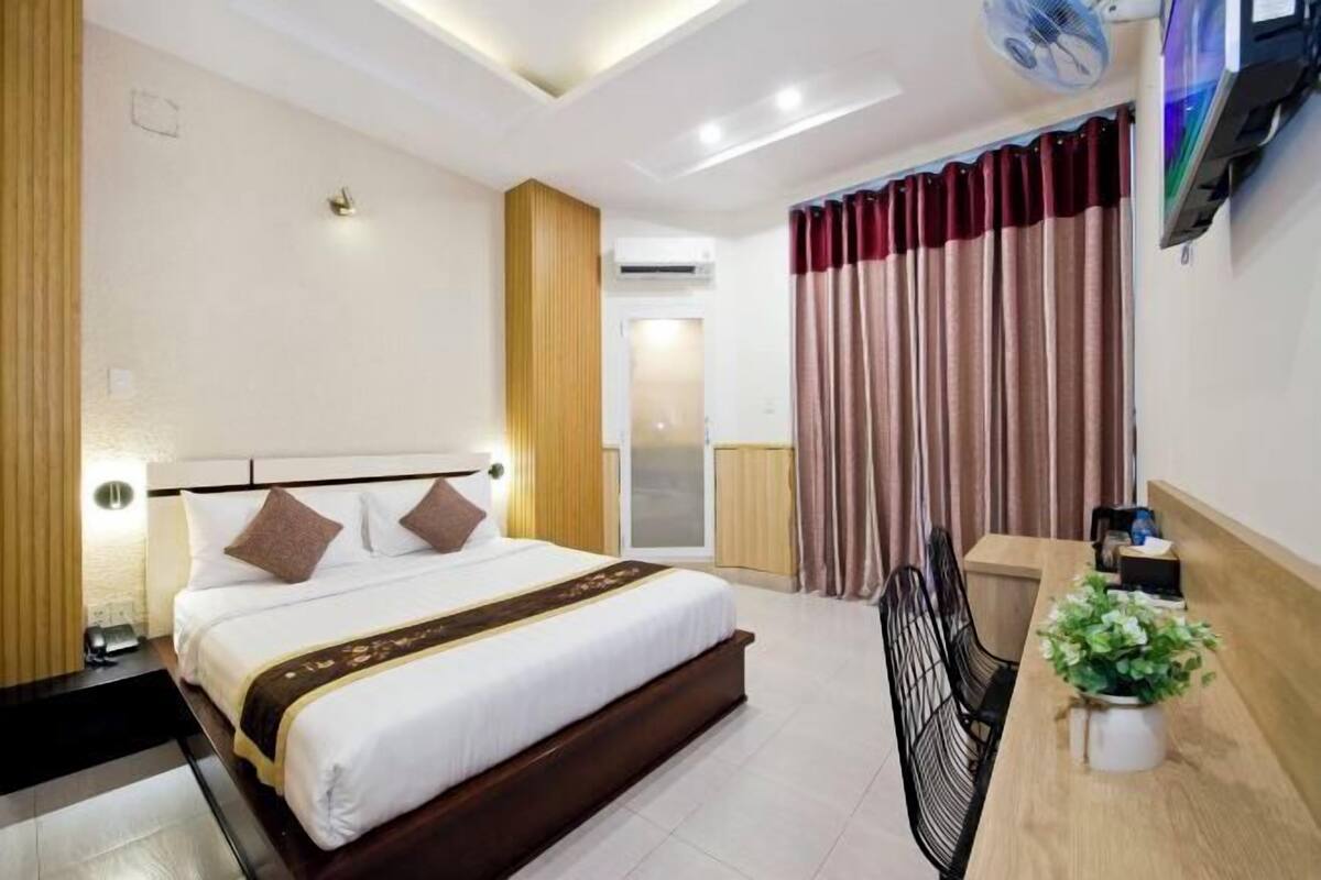 Una habitación de hotel con una cama grande, una mesita de noche y un pequeño escritorio con una planta.