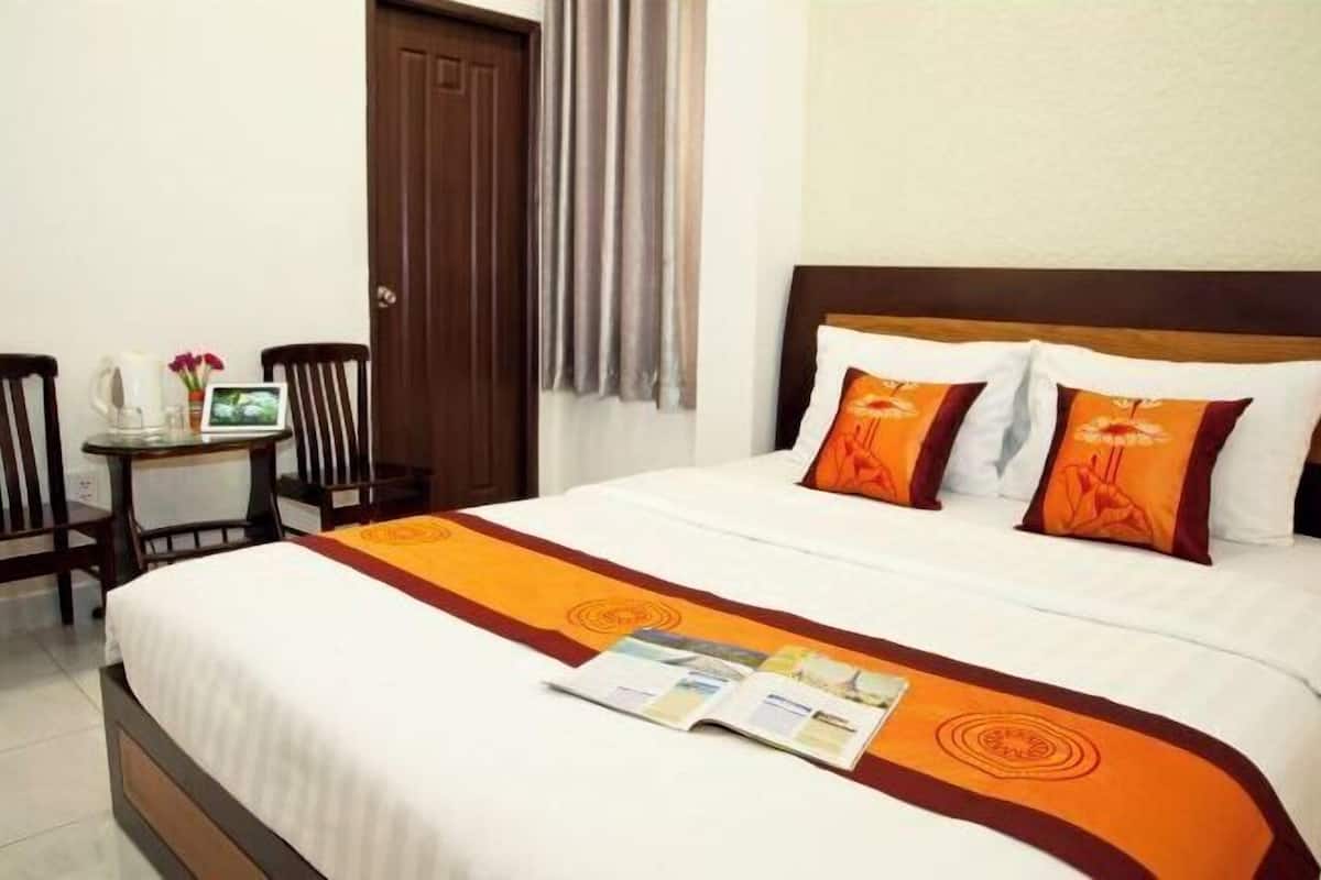 Una habitación de hotel con una cama, una mesita de noche con una lámpara y una silla.