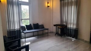 Ένα δωμάτιο με έναν πάγκο, ένα μικρό τραπέζι και ένα παράθυρο με κουρτίνες.
