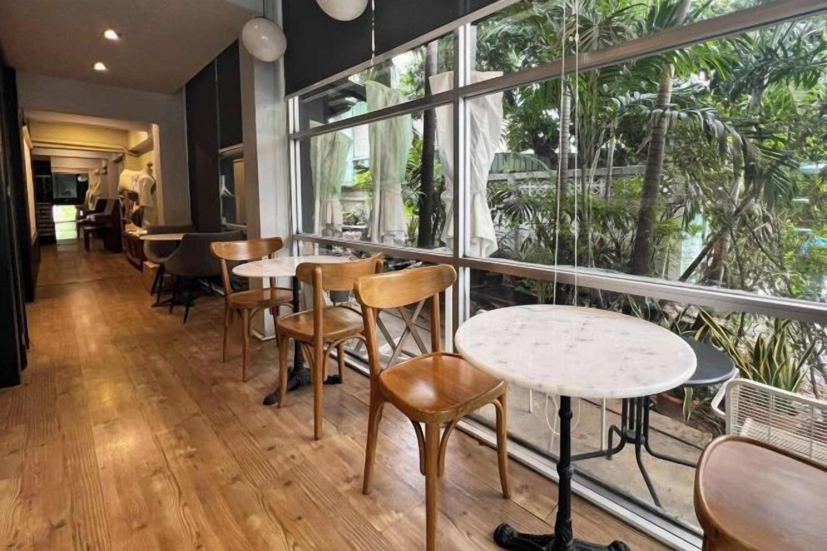 A restaurant with wooden flooring, round tables, and chairs.