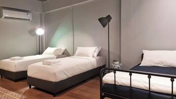 A hotel room with two beds, a bedside table, a lamp, and an air conditioning unit.
