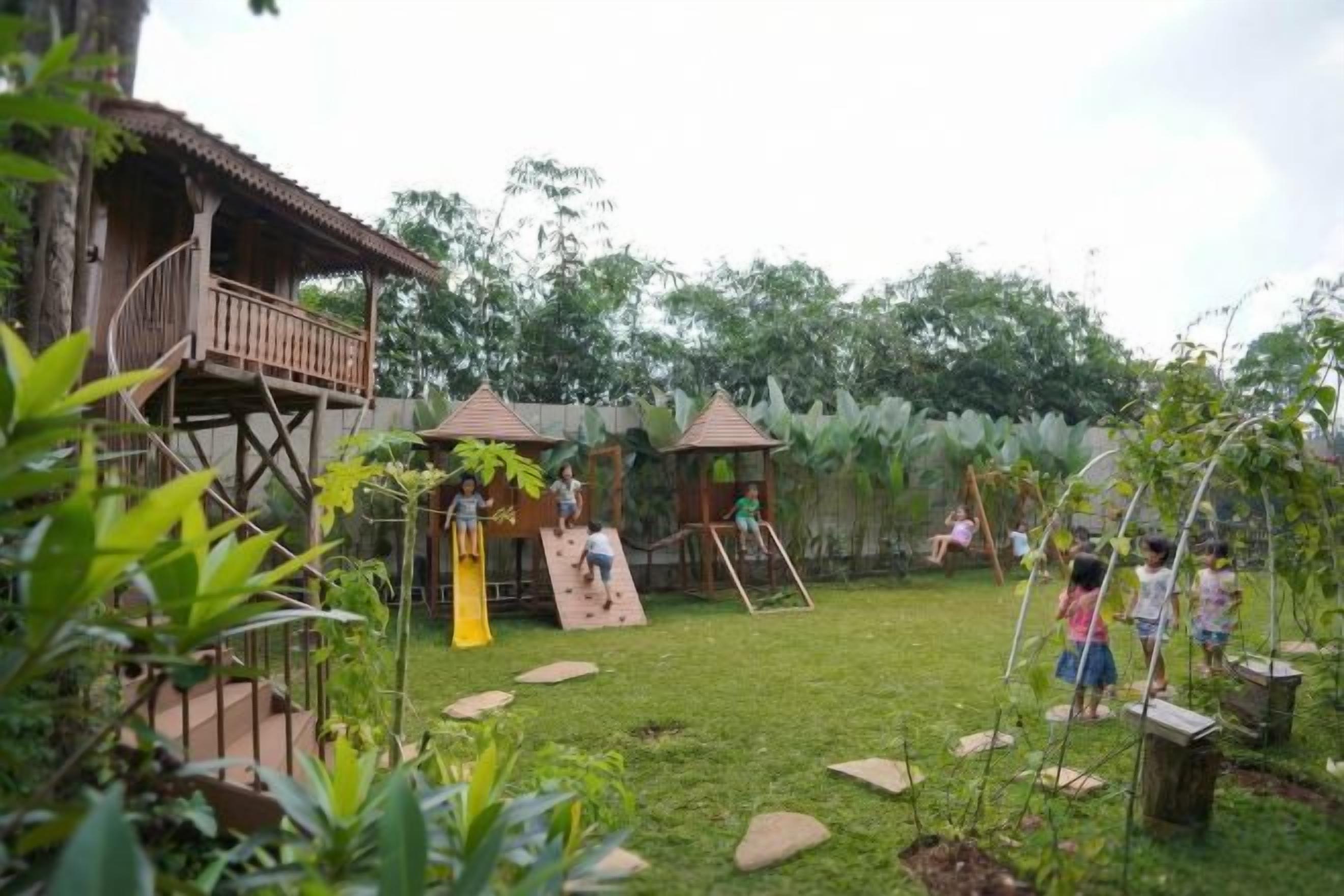 Une structure de jeu en bois, installée dans un espace extérieur verdoyant, avec des marches et des toboggans.