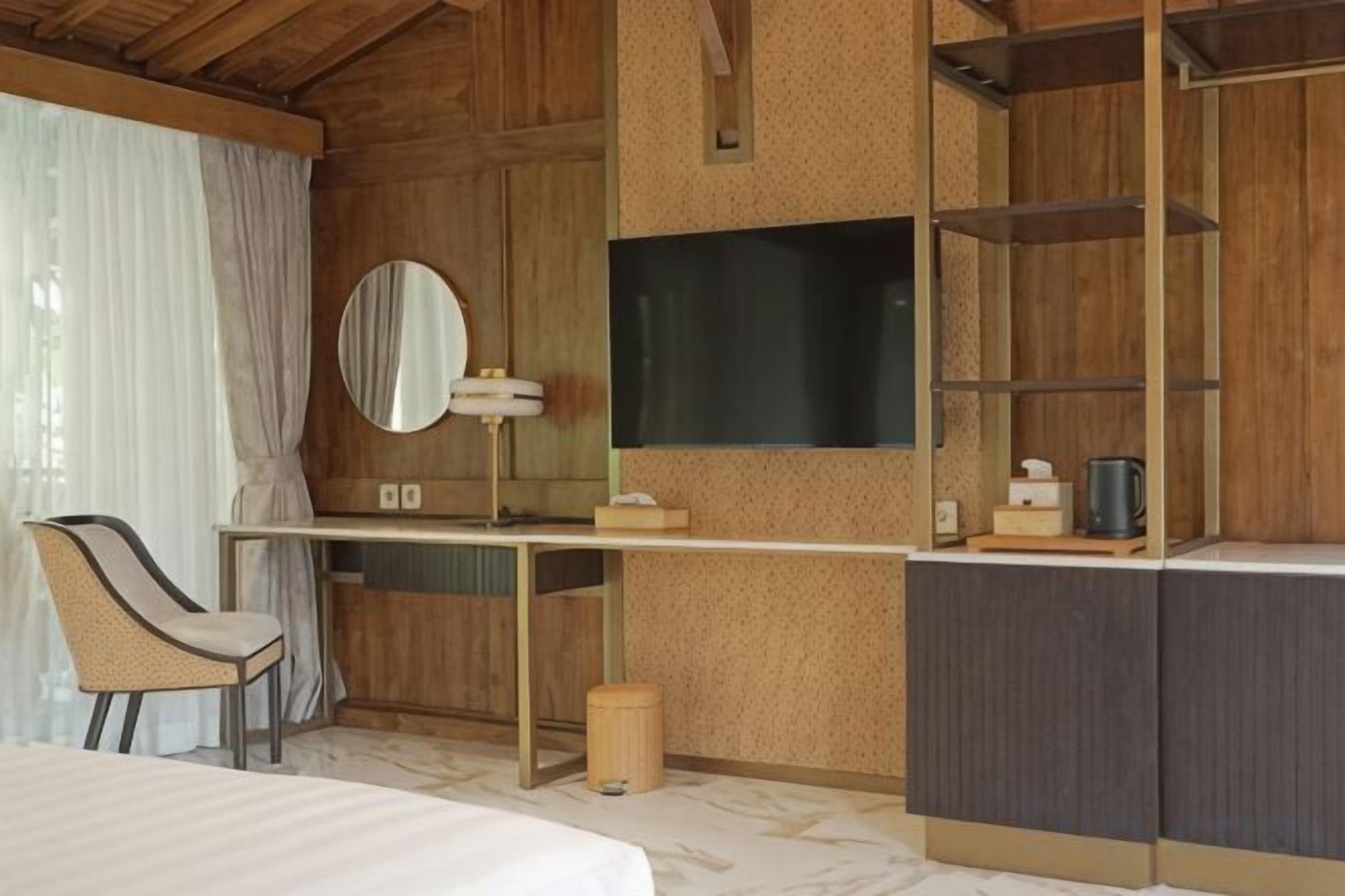 Une chambre à coucher comprenant un lit, un bureau, une chaise, un miroir, une télévision et des étagères intégrées.