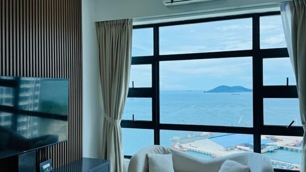 A room with a large window, a bed, a TV, and an air conditioning unit. - JESSELTON QUAY BY KC SUITE (Kota Kinabalu)