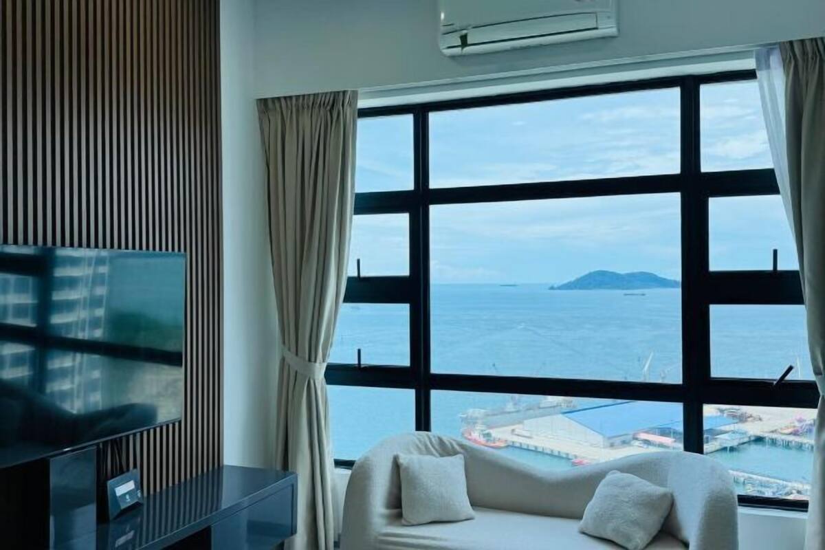Een kamer met een groot raam, een bed, een televisie en een airconditioning.