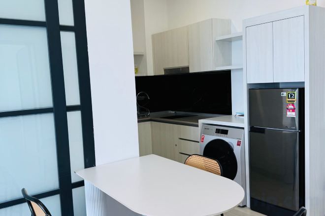 Una cucina compatta con lavatrice, frigorifero e zona pranzo con tavolo.