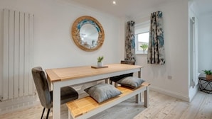 Une pièce moderne avec une table en bois, un banc et un miroir rond accroché au mur.