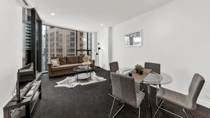 A modern living room with a sofa, coffee table, and dining area. - A Cozy Apt, Only a 5-min Walk to Victoria Market (Carlton)