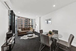 A modern living room with a sofa, coffee table, and dining area.