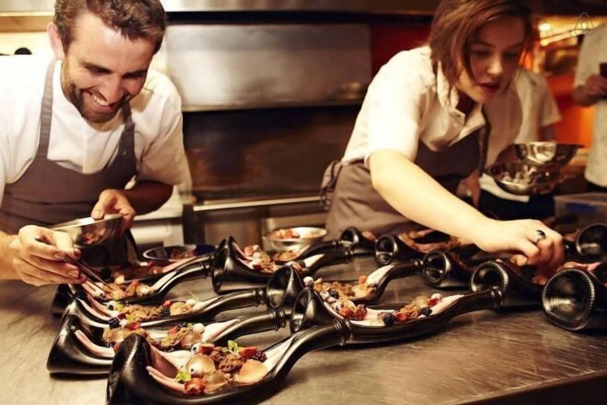 A chef preparing food in a professional kitchen with stainless steel surfaces and specialized cooking equipment.
