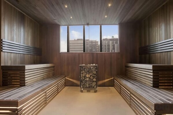 A sauna room with benches and a stone pillar, large windows, and a view of the city. - A Cozy Apt, Only a 5-min Walk to Victoria Market (Carlton)
