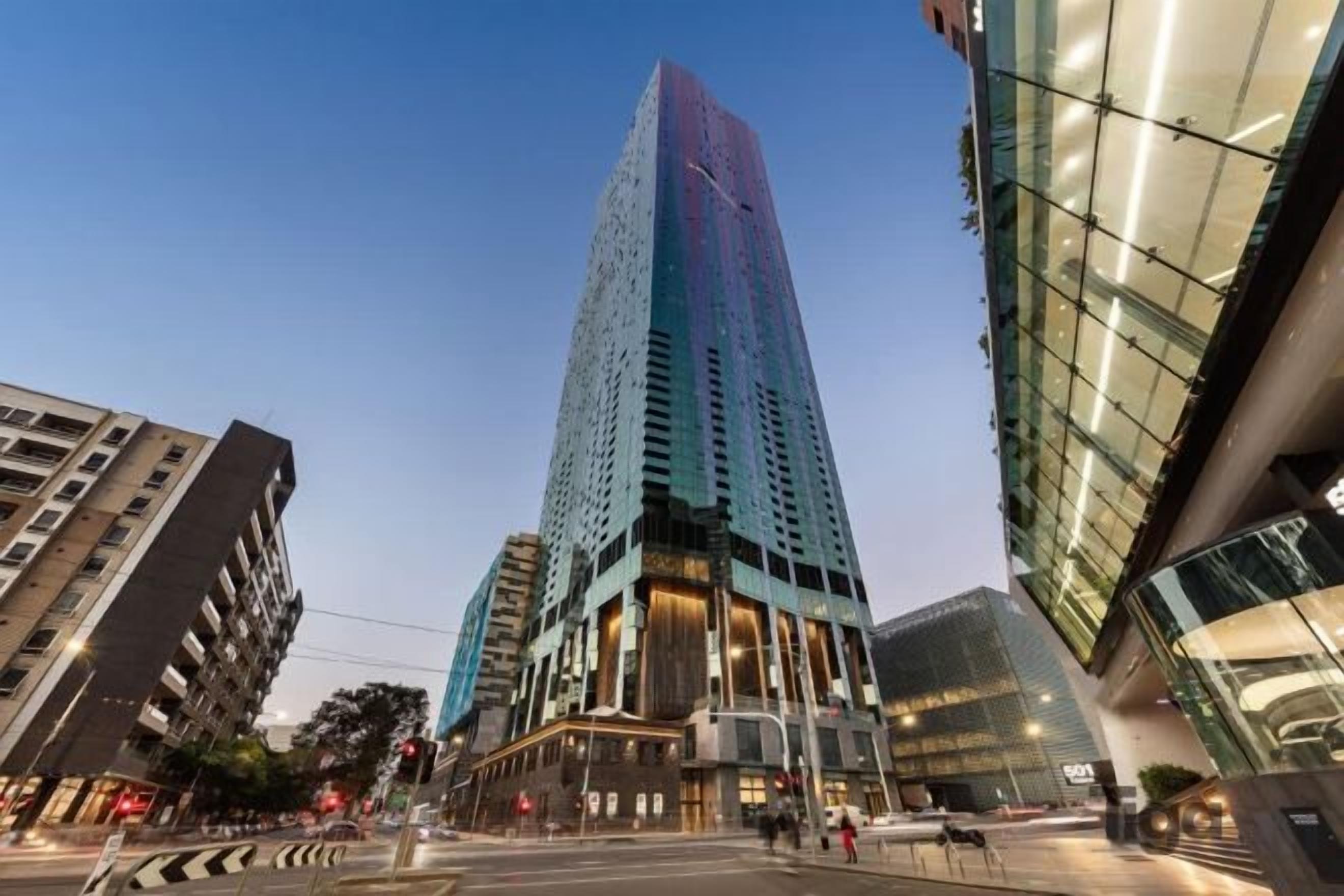 A high-rise building with a modern glass facade, located in an urban setting with other buildings around.