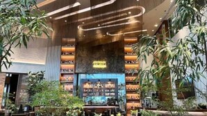 A modern interior with a central bar area, surrounded by shelves of products and potted plants. - Cozy 1 Studio - The Residences BGC Taguig (Taguig)
