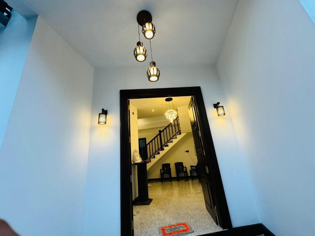 Un pasillo que conduce a una escalera, con un aplique en el techo y apliques a cada lado.