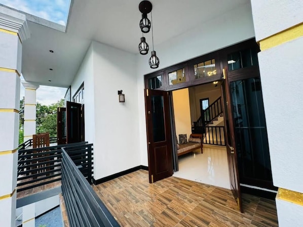 A modern interior with a wooden floor, a staircase, and a view into a room with a staircase. - Royal Palace Mirissa (Mirissa)
