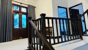 Un interior moderno con una escalera, puertas de madera y vistas al exterior.