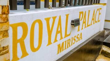 A sign with "ROYAL PALACE MIRISSA" written in large yellow letters on a white background.