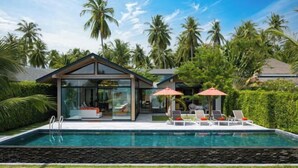 A modern house with a swimming pool, glass walls, and outdoor seating. - Baan Talay BeachFront Pool Villa B (Koh Samui)