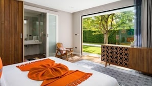 A modern bedroom with a large bed, a wooden wardrobe, a glass shower enclosure, and a view of a garden through a sliding glass door. - Baan Talay BeachFront Pool Villa B (Koh Samui)