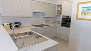 A modern kitchen with white cabinets, stainless steel appliances, and a marble countertop. - Apt 16, Seaviews, Slps 5 Indoor Heated Pool (Croyde)