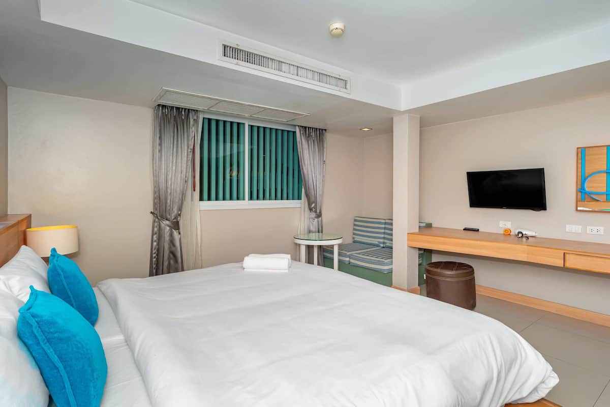 Een hotelkamer met een bed, een televisie, een tafeltje en een stoel.