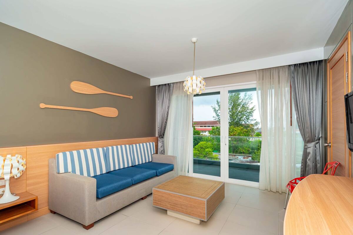 Een moderne woonkamer met een bank, een houten salontafel, een televisie en uitzicht op de omgeving.
