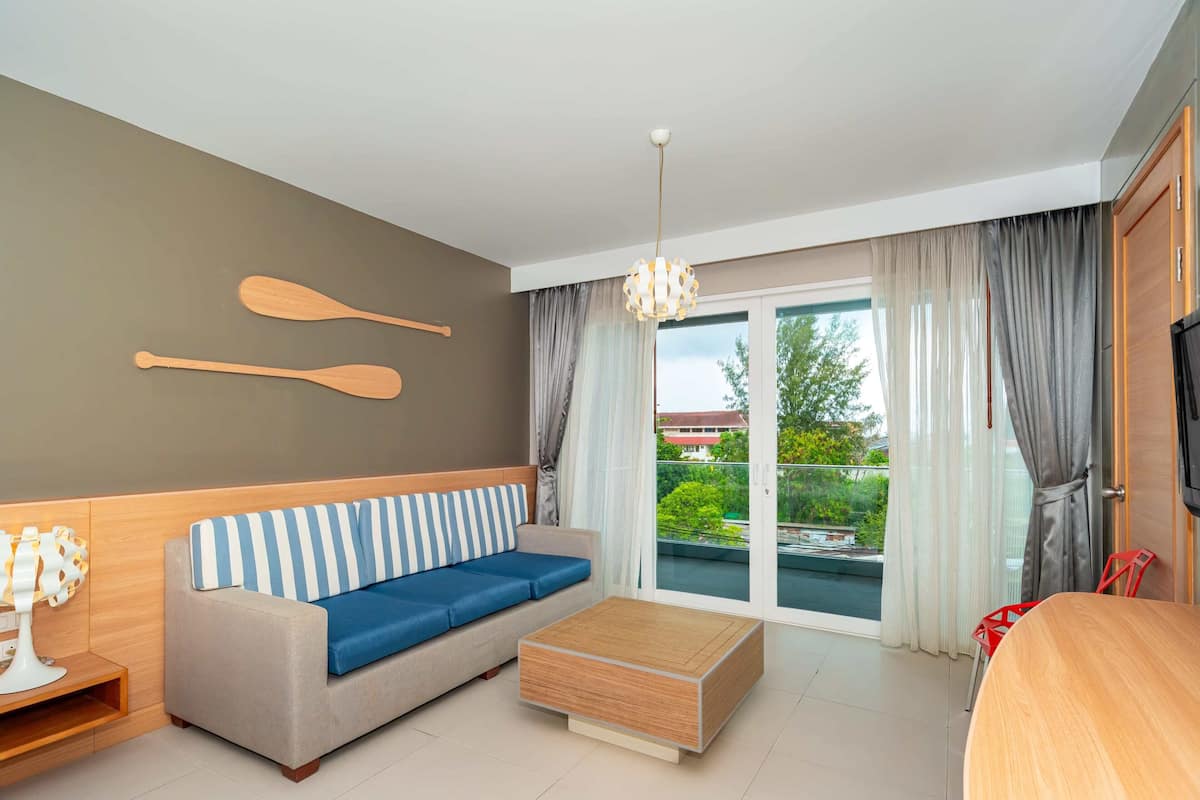 Een moderne woonkamer met een bank, een houten salontafel, een televisie en uitzicht op de omgeving.
