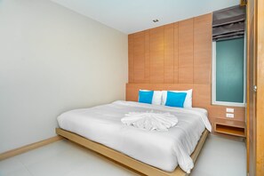 A hotel room with a wooden headboard, a bed with white bedding, and a window with a view. - Ratana Platinum Resort Kamala (Kamala)