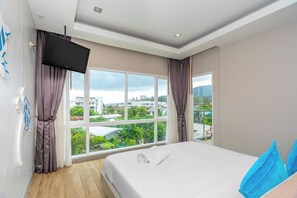 A bedroom with a bed, a TV, and a large window with curtains. - Ratana Platinum Resort Kamala (Kamala)