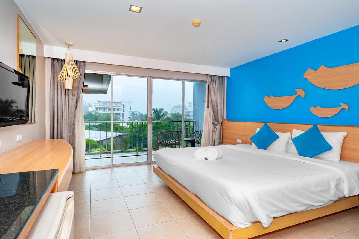 Een hotelkamer met een bed, een televisie, een balkon met uitzicht en een blauwe muur met houten decoraties.