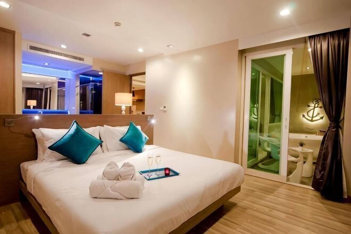 Hotelkamer met een bed, een badkamer, een spiegel en een schuifdeur naar een balkon.