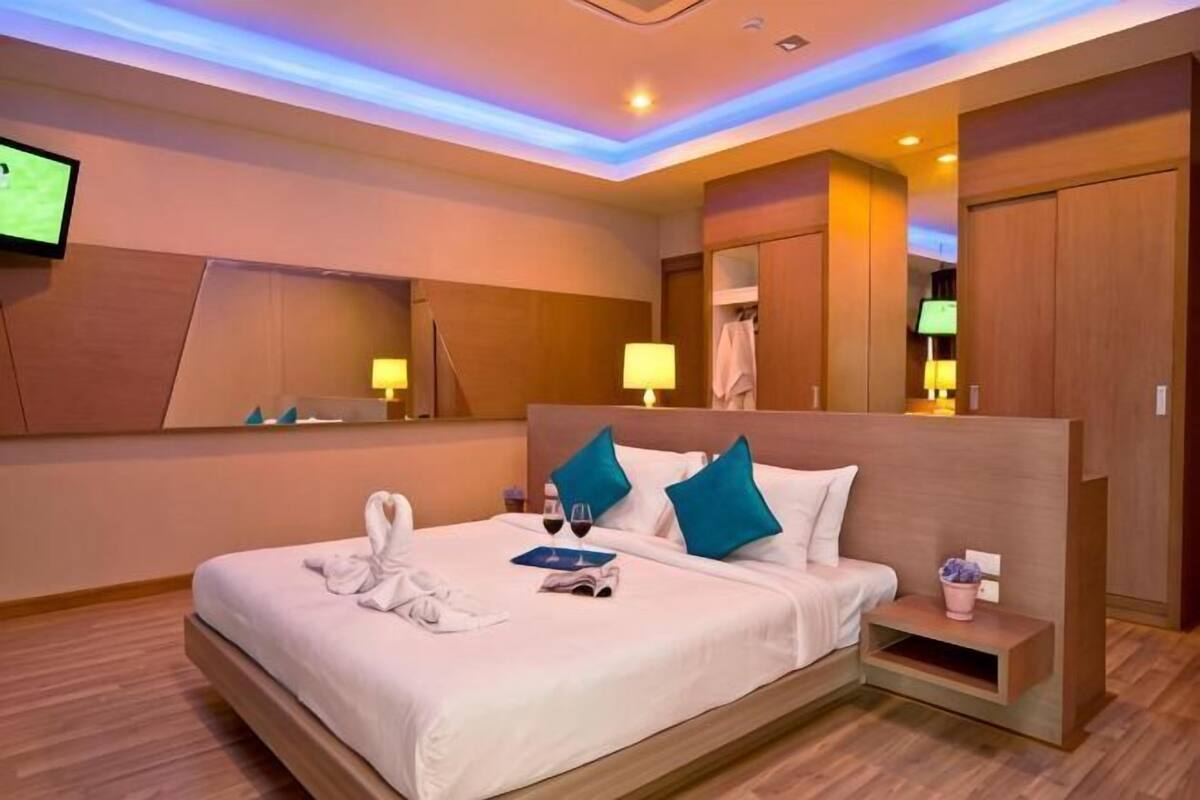 Een hotelkamer met een groot bed, nachtkastjes, een televisie en een spiegel.