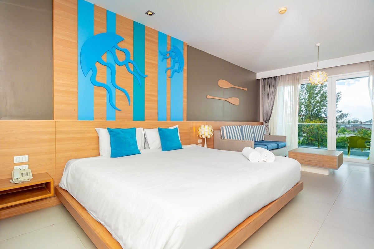 Une chambre d’hôtel moderne avec un grand lit, une tête de lit en bois, un téléphone fixé au mur et une vue sur l’extérieur.