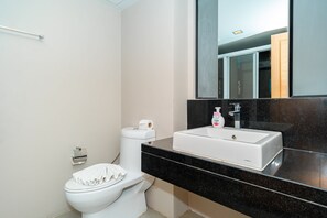 A modern bathroom with a white toilet, a black countertop, a white sink, and a mirror above the sink. - Ratana Platinum Resort Kamala (Kamala)