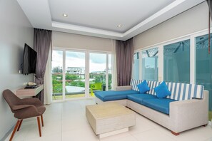 A modern living room with a sofa, a chair, a coffee table, and a TV mounted on the wall. - Ratana Platinum Resort Kamala (Kamala)