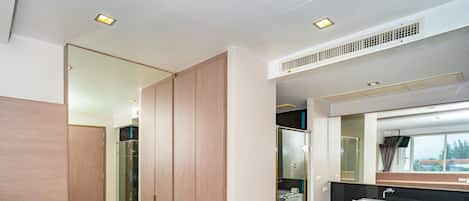 Une salle de bain moderne avec un grand miroir, un lavabo et une douche à l’italienne.