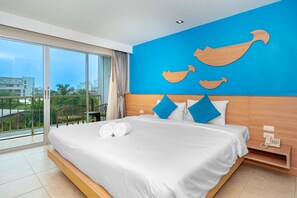 Habitación de hotel con una cama grande, un balcón con vistas y una pared azul decorada con adornos de madera.