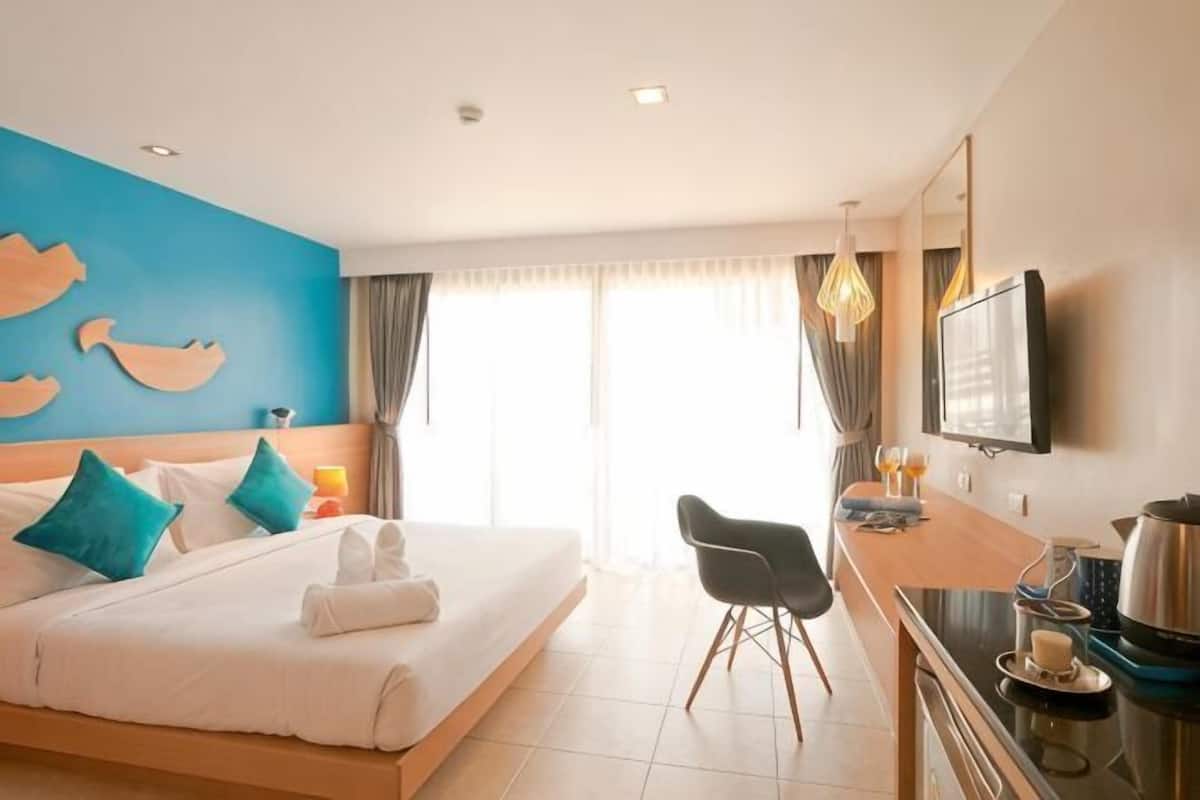 Een hotelkamer met een bed, een bureau, een stoel, een televisie en een raam met gordijnen.