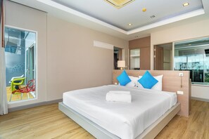 A modern hotel room with a large bed, a sliding door to a balcony, and a view of the cityscape. - Ratana Platinum Resort Kamala (Kamala)