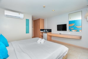 A hotel room with a bed, a TV, a desk with a computer, and a kitchenette. - Ratana Platinum Resort Kamala (Kamala)
