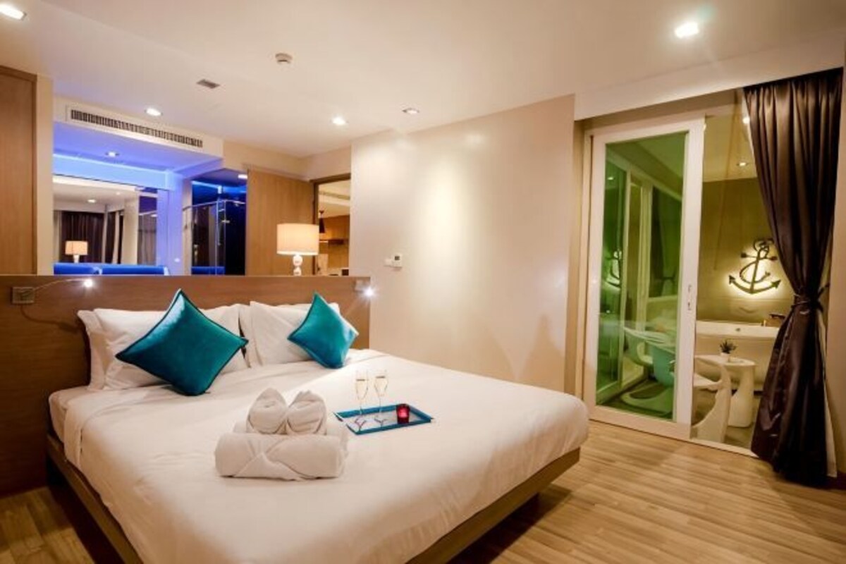 Une chambre d’hôtel comprenant un lit, une salle de bain, un miroir et une porte coulissante donnant sur un balcon.