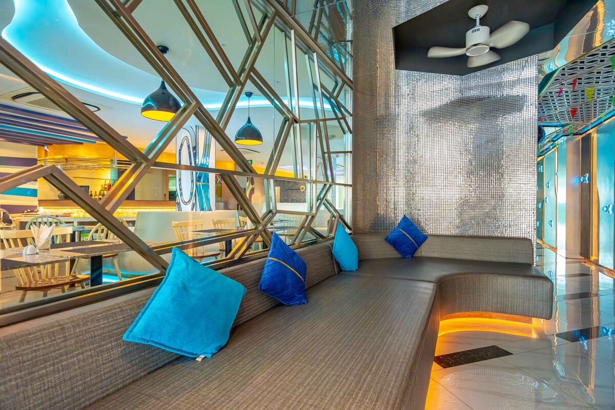 A modern interior with a seating area, a ceiling fan, and a view of the dining area.
