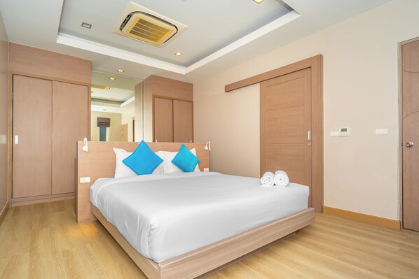 A hotel room with a large bed, wooden wardrobe, a mirror, and a ceiling fan. - Ratana Platinum Resort Kamala (Kamala)